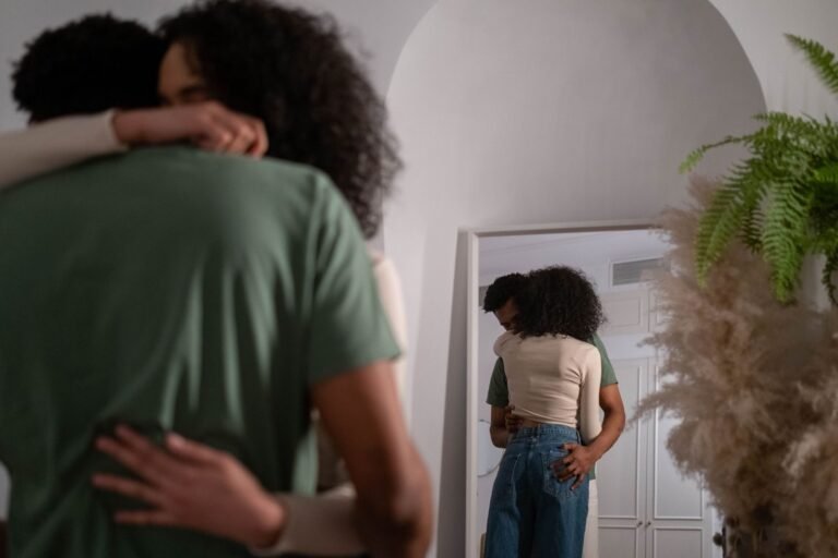 Casal se abraçando em casa, diante do espelho